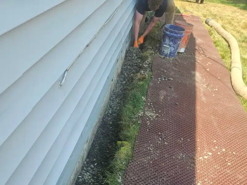 LUX crew hand-removing failing french drain and excavated soil to expose foundation footing in Alexandria VA