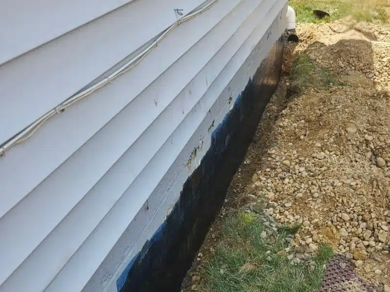 Black elastomeric waterproofing base coat applied to exposed foundation wall during exterior waterproofing in Alexandria VA.