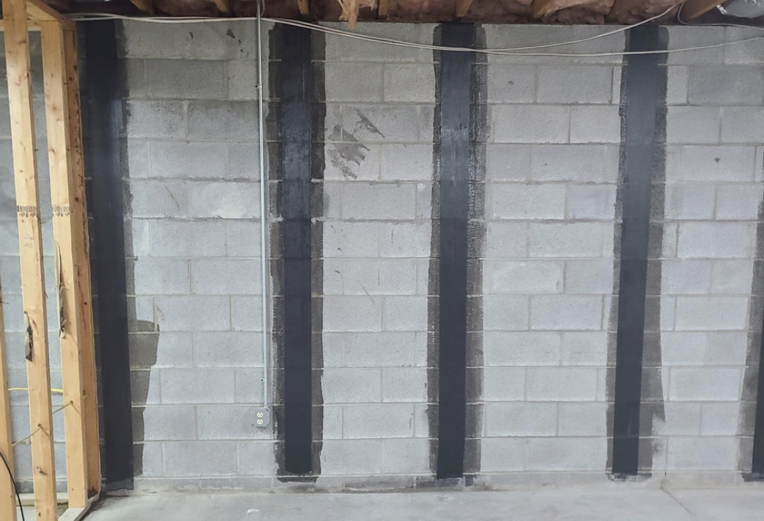 Completed carbon fiber strap reinforcement system installed on concrete block foundation wall after crack repair in Winchester, VA.