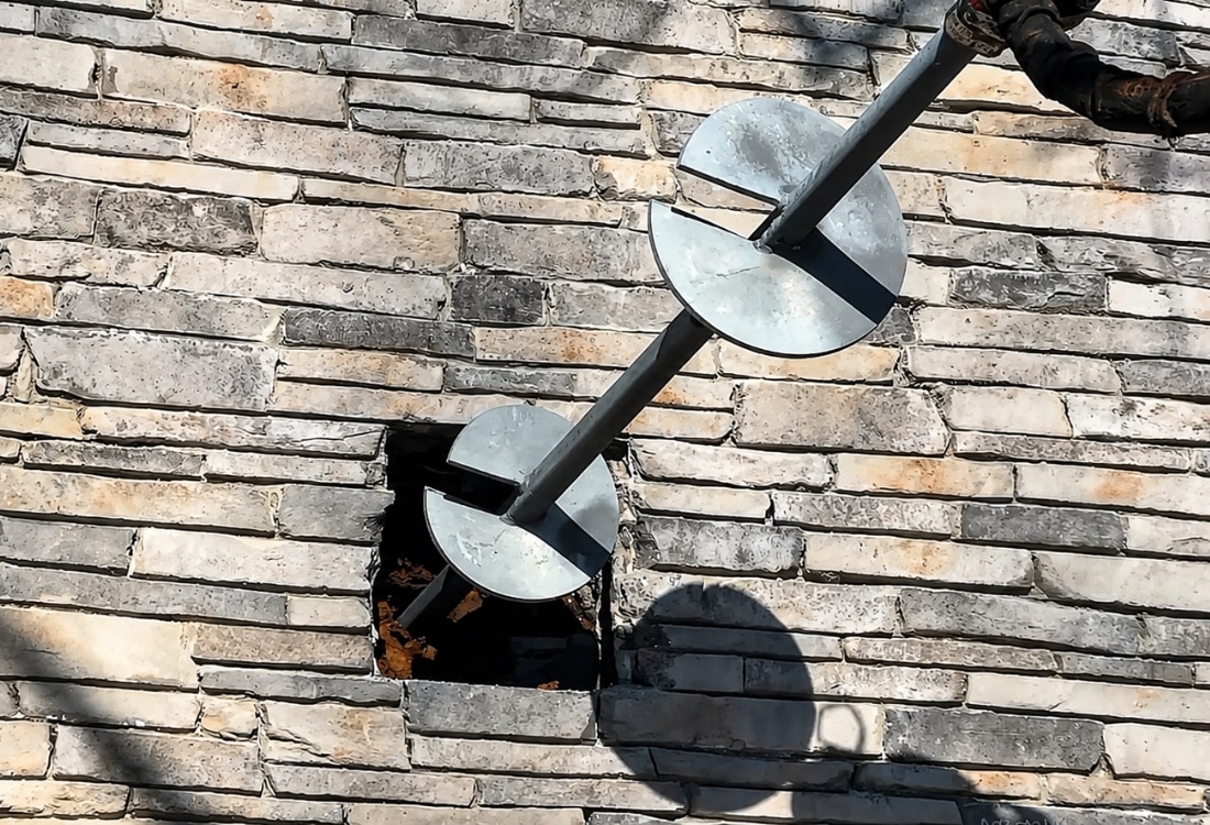 Ongoing helical pier installation in retaining foundation showing helical pier do works in Winchester, VA.