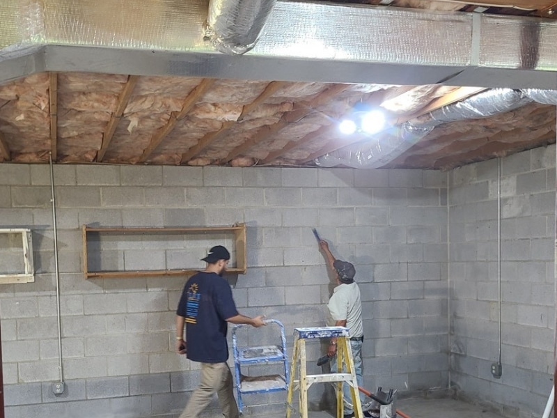 Technicians cleaning surface wall for soft bonding of epoxy and carbon fiber straps to repair cracks in Winchester, VA.