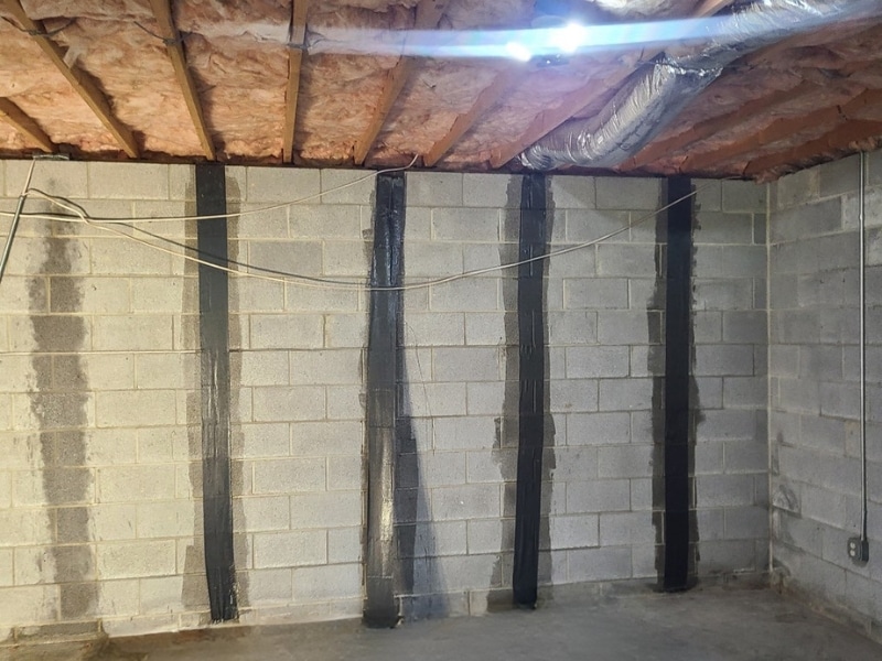 Carbon fiber straps bonded to a concrete wall with structural epoxy after foundation wall crack repair in Winchester, VA.