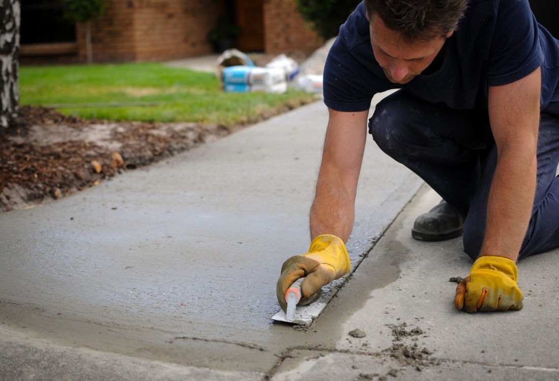 Worker repairing a damaged concrete driveway surface in Ashburn, VA.