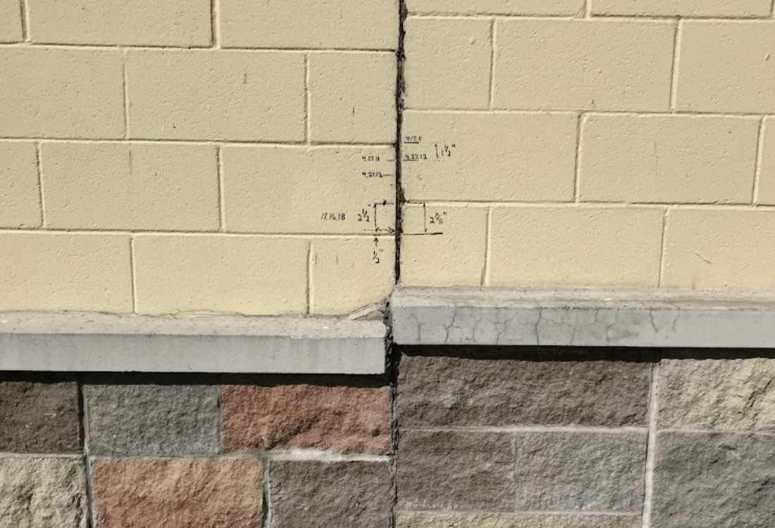 A concrete wall crack with recorded measurements tracked as part of evaluation for concrete wall crack repair in Winchester, VA.