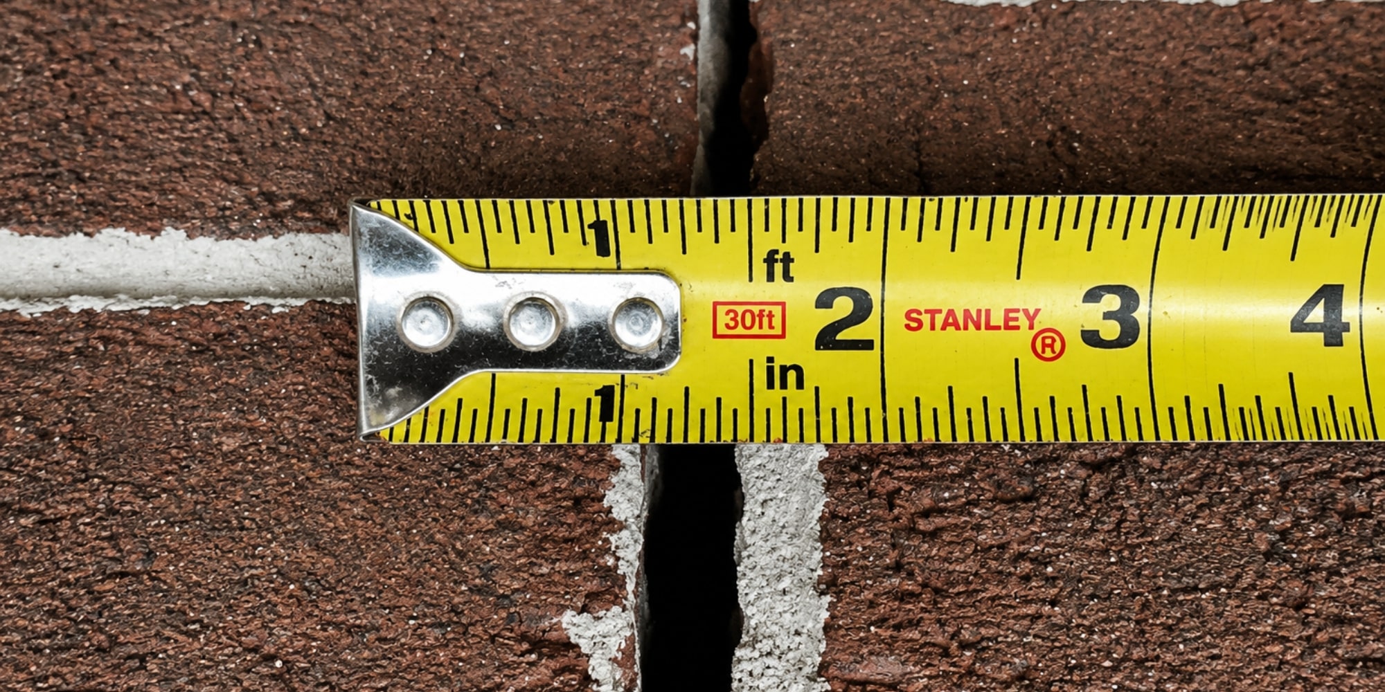 A tape measure recording the width of a concrete wall crack for professional concrete wall crack repair evaluation in Northern VA.