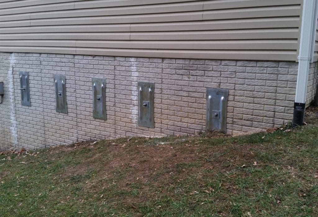Installed wall anchor plate on a finished foundation wall, showing how wall anchors work for bowing walls in Fairfax, VA.