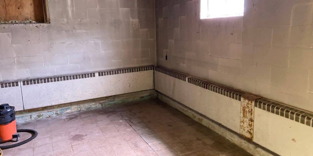Unfinished basement with moisture stains along foundation walls that needs waterproofing before finishing in Northern Virginia.