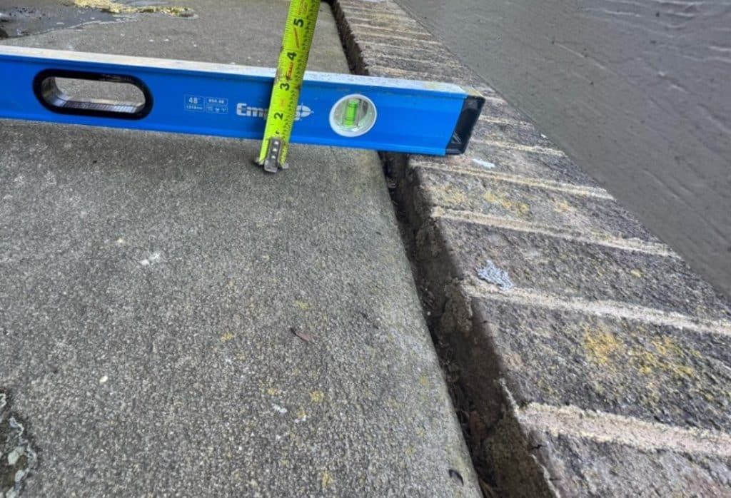 Level showing height difference between sunken concrete and adjacent raised surface that need concrete lifting in Winchester, VA.