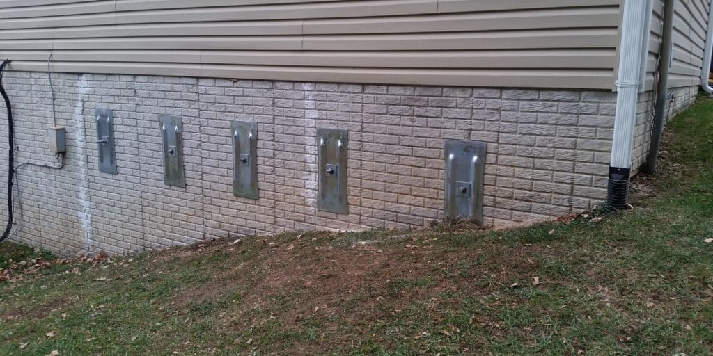 Five installed wall anchor plates stabilizing a foundation wall in Northern Virginia
