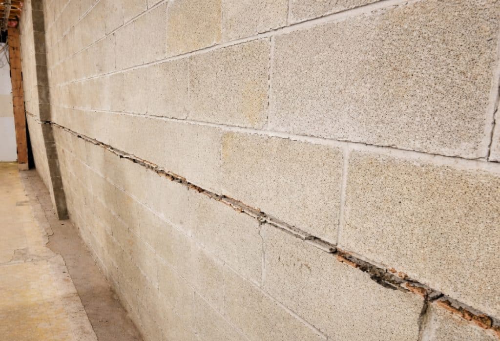 A basement wall bowing inward from pressure caused by saturated clay soil outside, a common cause of water in basement in Bristow, VA.