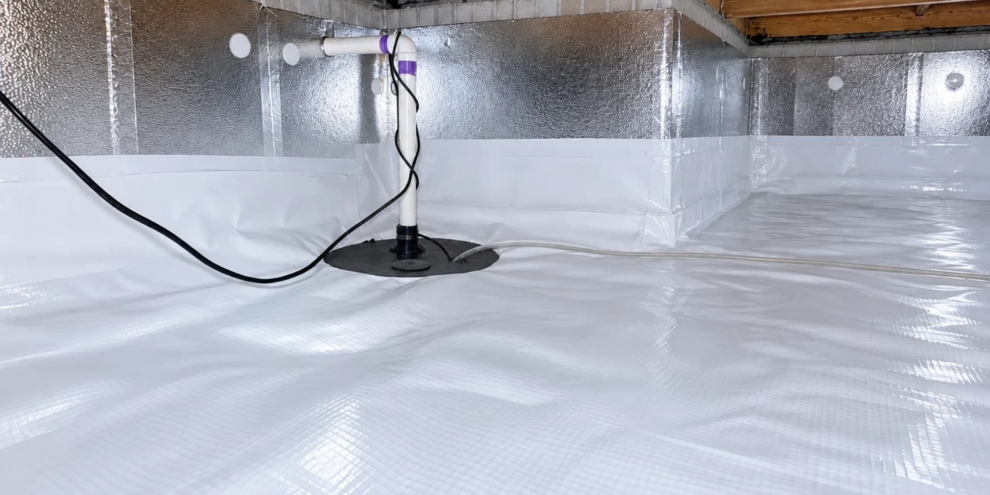 Installed vapor barrier and sump pump system showing the benefits of crawlspace waterproofing in Northern Virginia home.