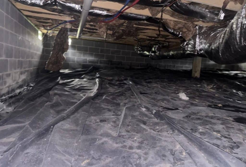 Stained insulation sagging from floor joists above a wrinkled ground cover, a sign that needs crawl space repair in White Post, VA.