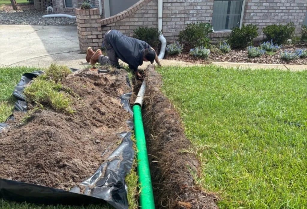 Expert installing an exterior drainage pipe in a yard trench to redirect water in the basement away in Berryville, VA.