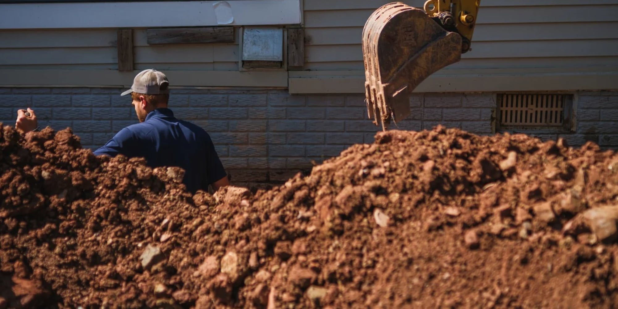 Crew excavating soil along a brick foundation wall, one of the factors that affect foundation repair cost in Northern Virginia.