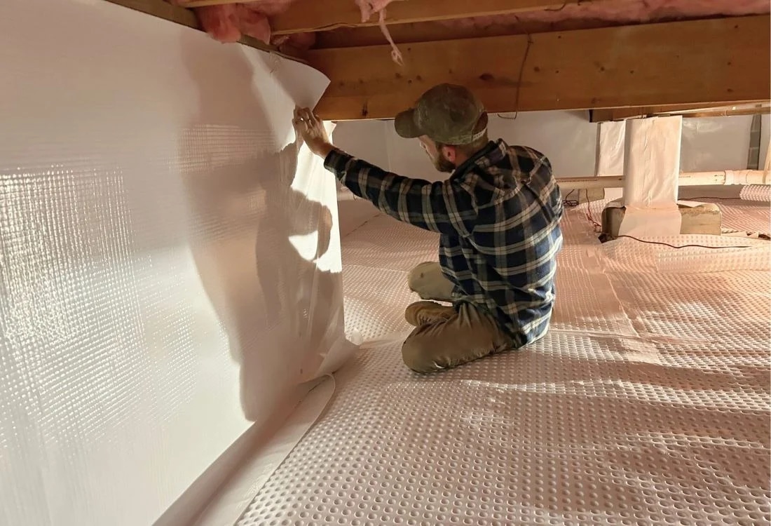 Contractor installing a vapor barrier during crawl space repair Winchester, VA.