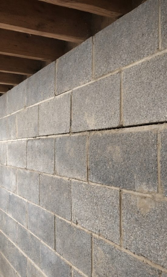 Concrete block basement wall with visible horizontal crack and inward lean viewed from inside a Winchester, VA, basement.